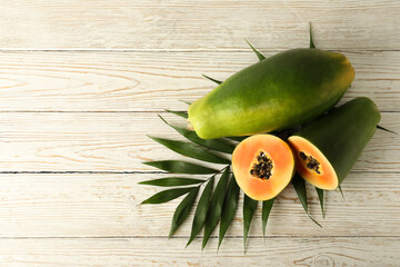 Ripe papaya with leaves on white wooden background