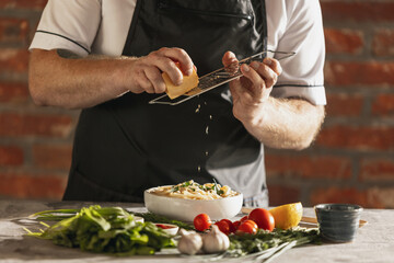 Cropped portrait of male chef, cook preparing carbonara in his cafe, restaurant kitchen. Concept of a correct, healthy diet. Tasting pasta