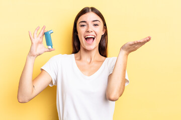 young hispanic woman feeling happy and astonished at something unbelievable. asthma concept