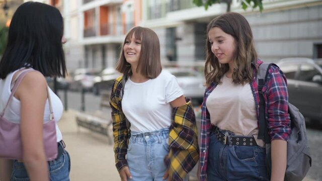 Three confident beautiful teenage girls stacking hands smiling standing on urban city street outdoors. Positive friends making deal meeting after school in town. Friendship and trust concept