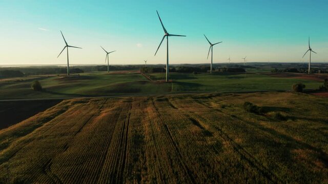Wind turbines at sunrise in countryside. Wind farm generating green energy