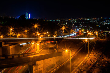 Car traffic on highways in the city at night. The movement of cars on bridges. Night city with...