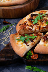 Pizza with chanterelle mushrooms and caramelized onion on yeast dough on the black wooden board. Italian food