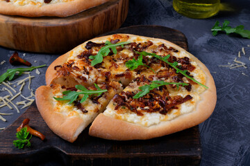 Pizza with chanterelle mushrooms and caramelized onion on yeast dough on the black wooden board. Italian food