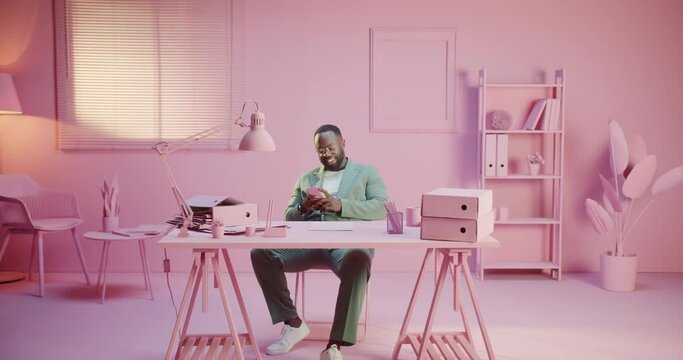 Office manager or director forgot about job enjoying smartphone app game or social network procrastination. Monochrome pink pastel design room studio. Monocolor creative office with monochrome rose