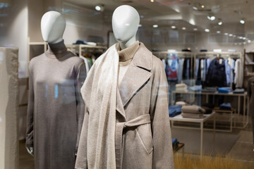 Two women's mannequins in the window of a large outerwear store. Autumn winter coat made of wool of...