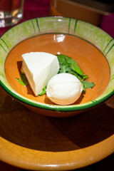 Italian antipasto dish with small pieces of white cheese and mozzarella ball