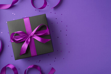 Top view photo of stylish black giftbox with purple ribbon bow confetti and satin ribbon on isolated violet background with empty space