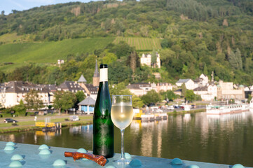 White quality riesling wine served on old bridge across Mosel river with view on old German town in...