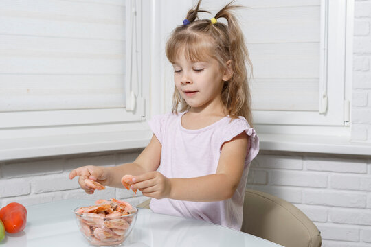 Caucasian Kid Girl Eating Shrimp At The Table. Healthy Food Concept. Seafood In The Diet Of Children