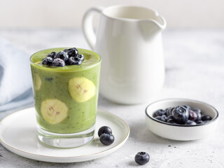 chia pudding with green superfood powder, banana, almond milk, blueberry. Healthy vegan food concept. Gray background.