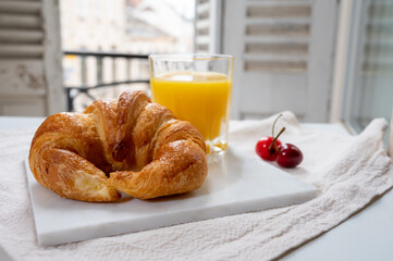 French breakfast, fresh baked croissant buttery pastry served with orange juice and old french houses on background