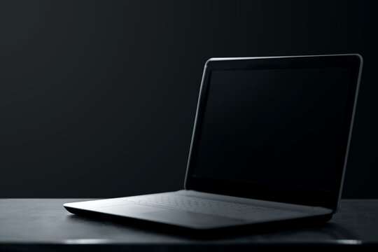 Creative background dark laptop stands on a dark background. Modern technology concept.