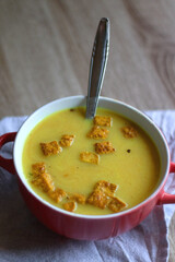 Bowl of vegan pumpkin and tofu curry soup on wooden table. Selective focus.