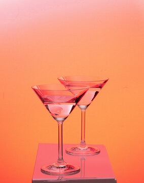 Two martini glasses transparent agains colorful background yellow red blue
green 