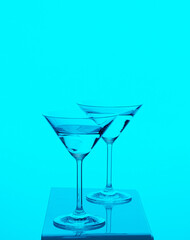 Two martini glasses transparent agains colorful background yellow red blue
green 