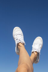 legs in sneakers on background of blue sky.