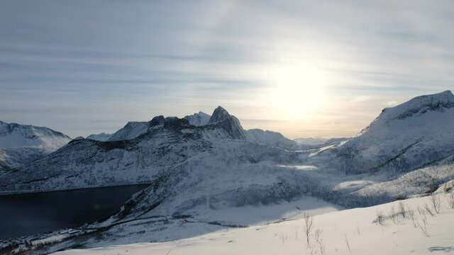 Snow mountain range on peak with sun halo at Segla island, Norway