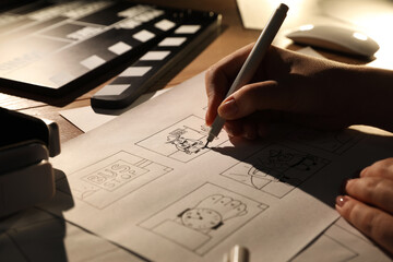Woman drawing cartoon sketches at workplace, closeup. Pre-production process