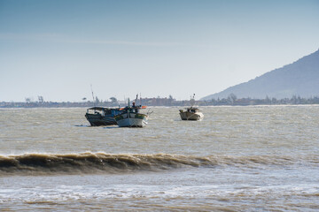 Obraz premium View of the beach of Rio das Ostras with the meeting of the river in Rio de Janeiro. Sunny day, blue sky. Yellow sand and some rocks. Wooden bridge to cross. Boats and fishing on the pier.