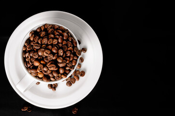 A white cup full of coffee beans. coffee beans on a black background. High quality photo