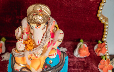 Idol of Lord Ganesh of a shadu clay a Hindu Religion God on the occasion of 'ganesh chaturthi' in India with flowers and decoration.