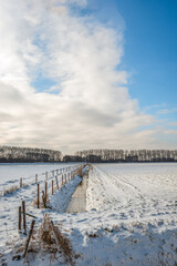 Dutch winter landscape with ditch and fences. The water in the ditch is partially frozen. The photo was taken in the Dutch province of North Brabant near the small village of Drimmelen.