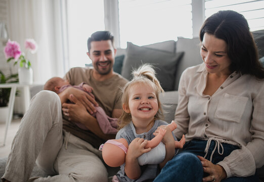 Happy young family with newborn baby and little girl enjoying time together at home.