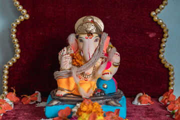 Idol of Lord Ganesh of a shadu clay a Hindu Religion God on the occasion of 'ganesh chaturthi' in India with flowers and decoration.