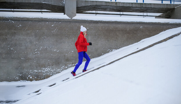 Side View Of Active Senior Woman Running Up The Stairs Outdoors In Snowy Winter.