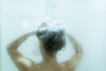 Unrecognizable Asian young woman enjoy taking a shower in the shower box in bathroom.