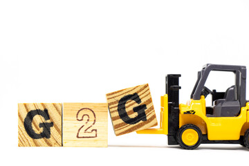 Toy forklift hold letter block G to complete word G2G (abbreviation of Government to government) on wood background