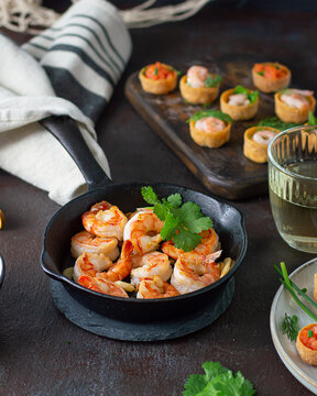 Fried shrimps prawns in a pan and croustades served on a white brown boards