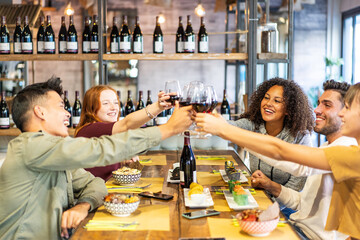 Multicultural friends toasting red wine at sushi bar restaurant - Food lifestyle concept with young people having fun together eating poke bowl - Bright vivid filter with focus on behind faces