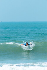 Surfer mężczyzna łapiący falę na desce na tle niebieskiego oceanu i błękitnego nieba.