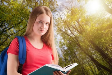 Woman holds book in her hands. Reading the book in a nature during beautiful sunset.