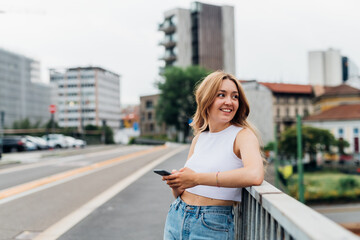 Fototapeta premium Young caucasian woman using smartphone looking camera positive and trustful in future