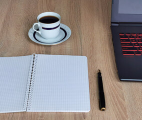 Close up cup of coffee, laptop computer, notebook and pen on wooden desk office. Workplace at home