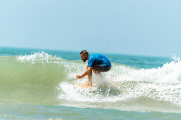 Mężczyzna surfer płynący na fali na tle błękitnego oceanu i nieba.