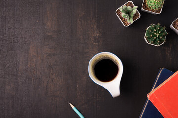 Coffee cup with cactus and book on the wooden background with copy space, top view