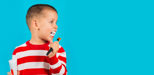 Banner child boy is brushing the vampire's teeth with an orange brush and is dressed in a striped red sweater. Carnival, holiday, health concept.