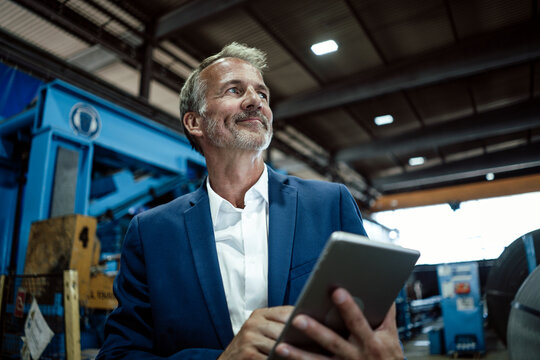 Senior businessman holding digital tablet at metal industry