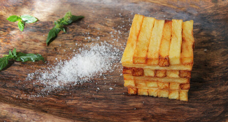 French fries
  on a wooden plate with spices and herbs.