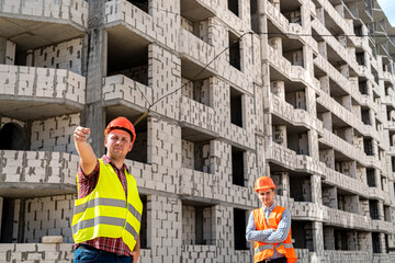 two young workers in uniform are considering a project to build a new house