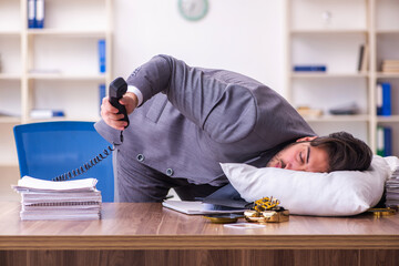 Young male employee in oversleeping concept