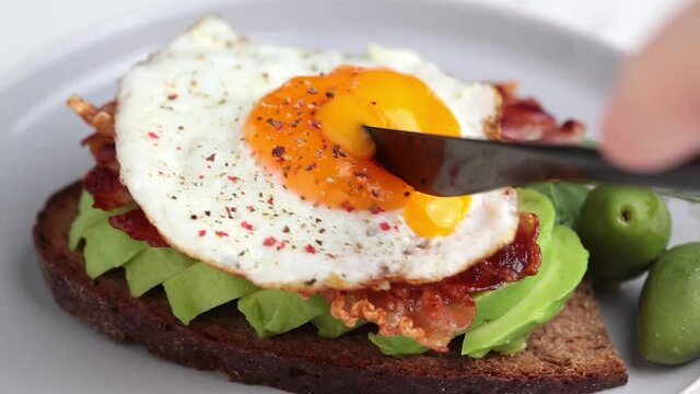 Toast with avocado, fried bacon and egg on a plate. Low-carb keto diet. Breakfast concept.