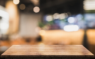 Empty wooden table top with lights bokeh on blur restaurant background.