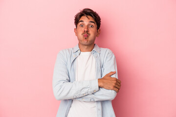 Young mixed race man isolated on white background blows cheeks, has tired expression. Facial...