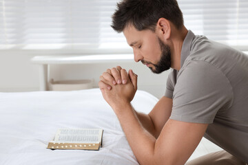 Obraz premium Religious man with Bible praying in bedroom