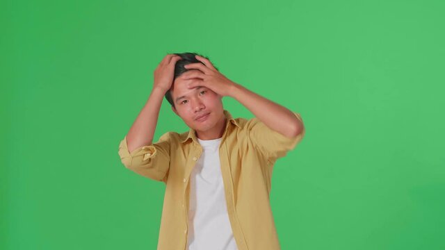 Asian Man Touching His Hair While Looking At Camera Like A Mirror On Green Screen In Studio
